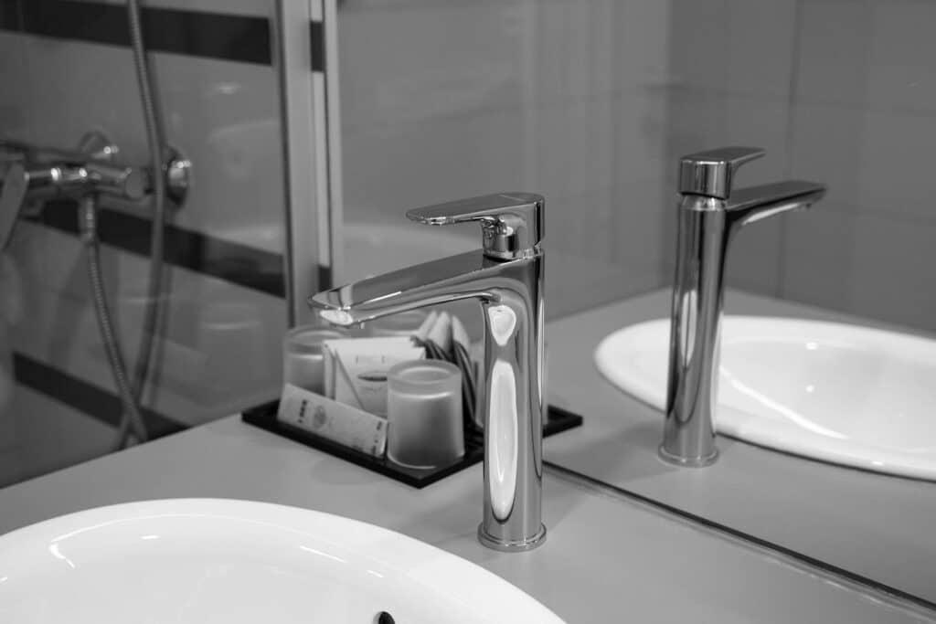 Stylish stainless steel faucet in black and white with mirror reflection in a modern bathroom.