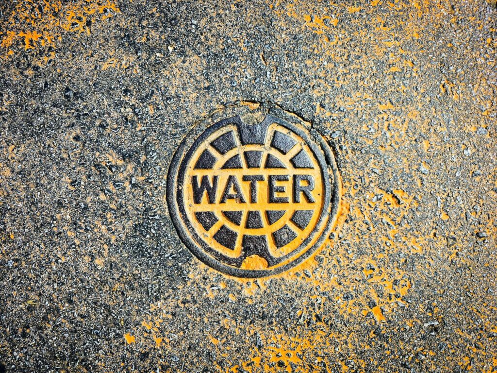 Colorful water utility cover on street pavement blends art with functionality.