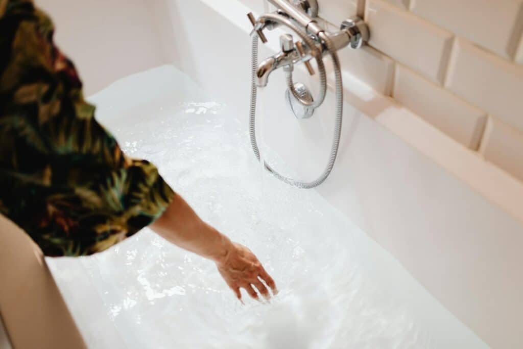 A close-up image of a hand touching water in a bathtub, focusing on the serene moment.