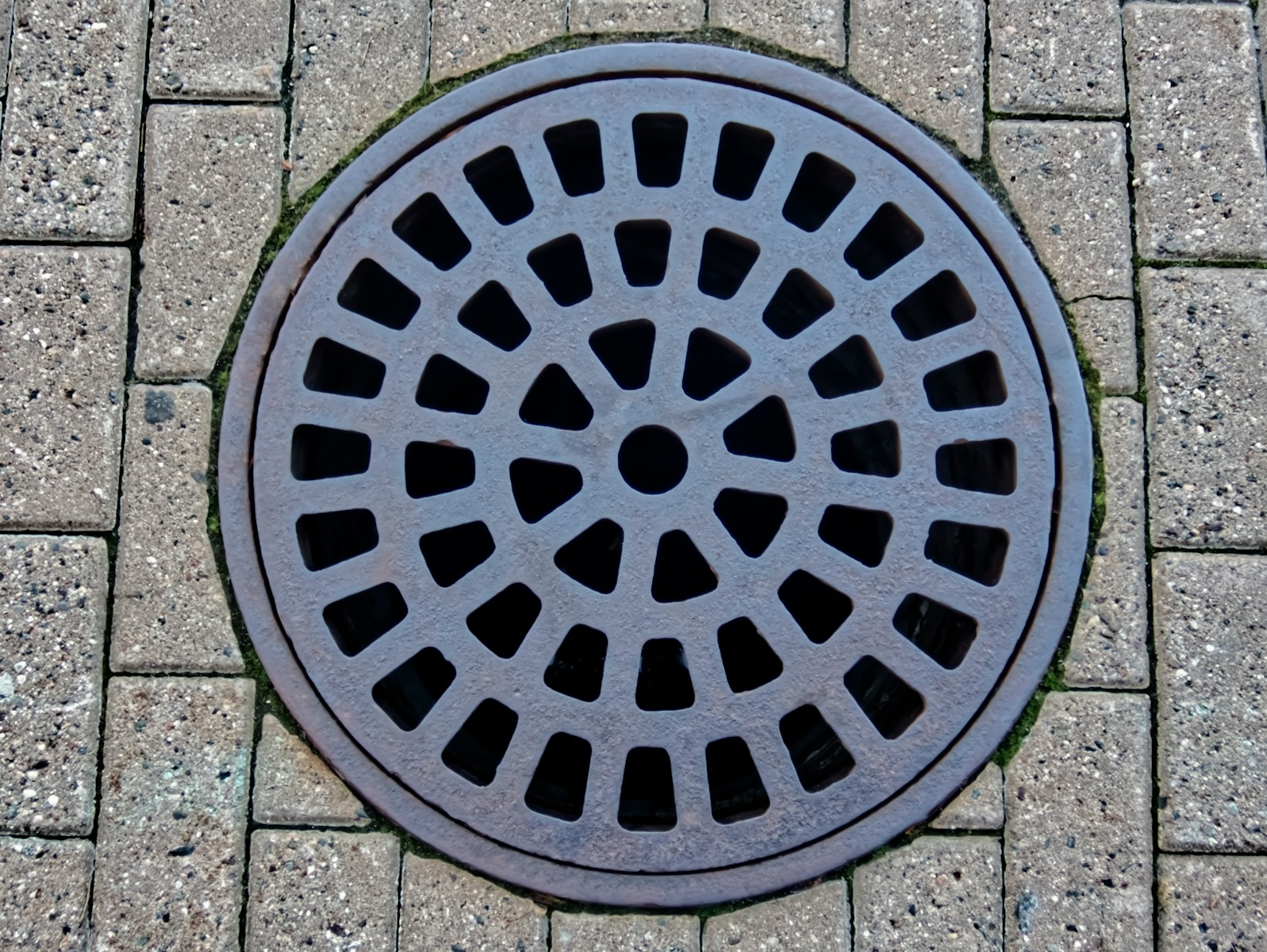 a manhole cover on a brick sidewalk Storm Drain & Catch Basin Cleaning