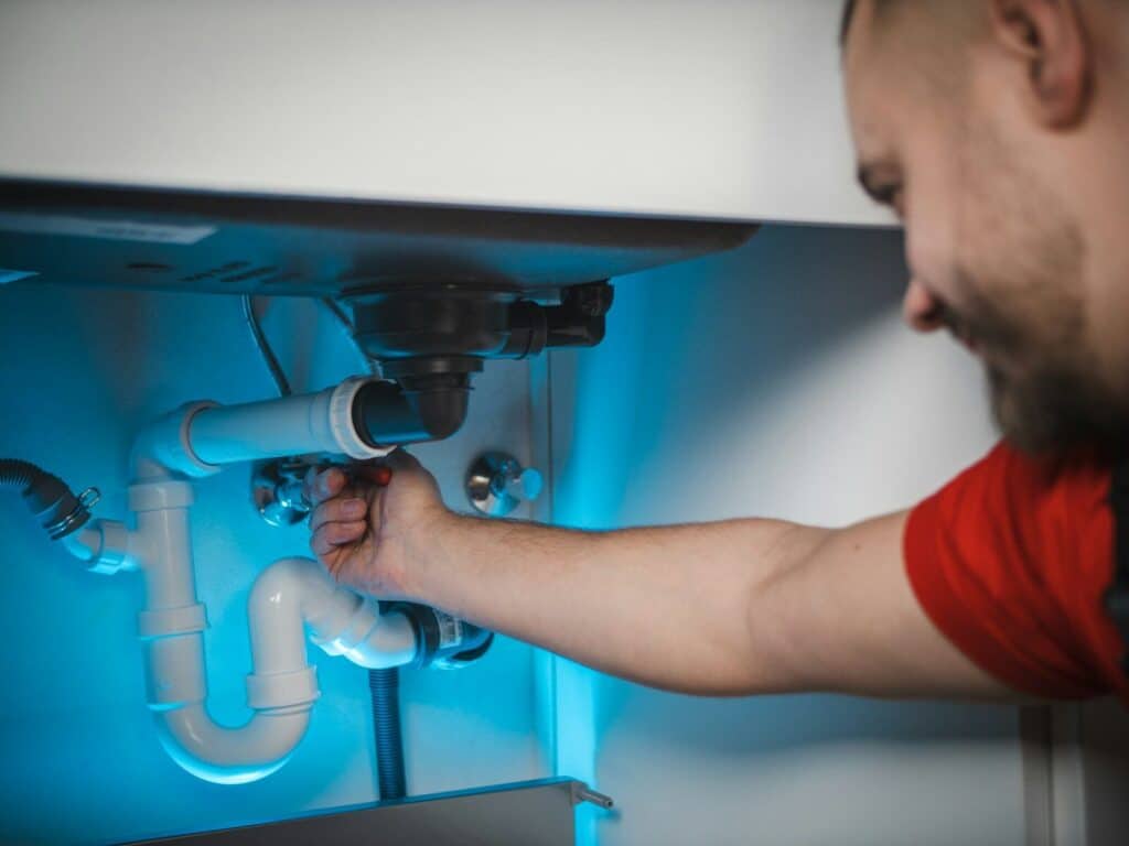 a man working on a pipe in a wall Plumber in College Park Maryland: Dependable Residential and Commercial Plumbing