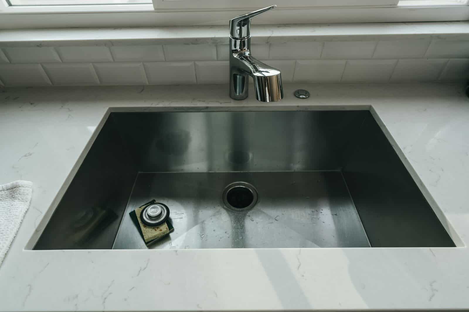 Photo by Henry Kobutra a sink with a faucet How to Unclog a Kitchen Sink in the Washington DC Area: A DIY Guide + When to Call the Pros