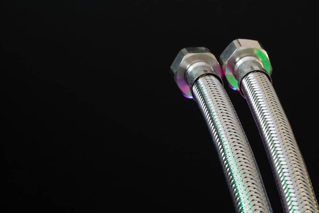 Close-up of metal flex pipes with hex nuts on a black background, showcasing industrial design.