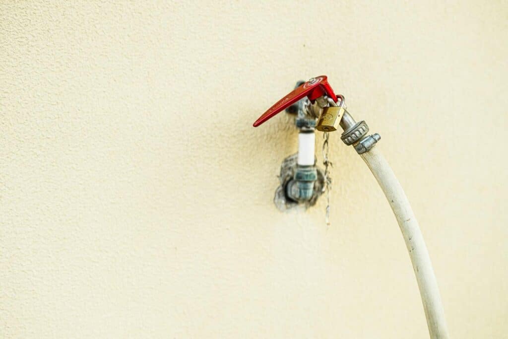 Detailed view of an outdoor water faucet with a bright red handle in Dubai, UAE.